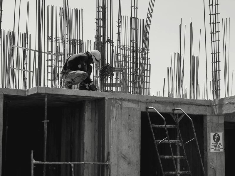 Trabajador con arnés armando acero de refuerzo sobre una losa de concreto.